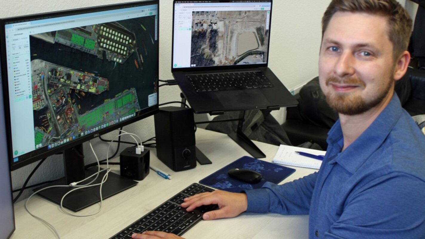 Sergey Sukhanov demonstriert die Plattform FlyPix AI zur Auswertung von Geodaten aus der Luft: Auf dem Bildschirm sind mit Hilfe von KI einzelne Container in einem Hafen grün markiert. Bild: Technische Universität Darmstadt